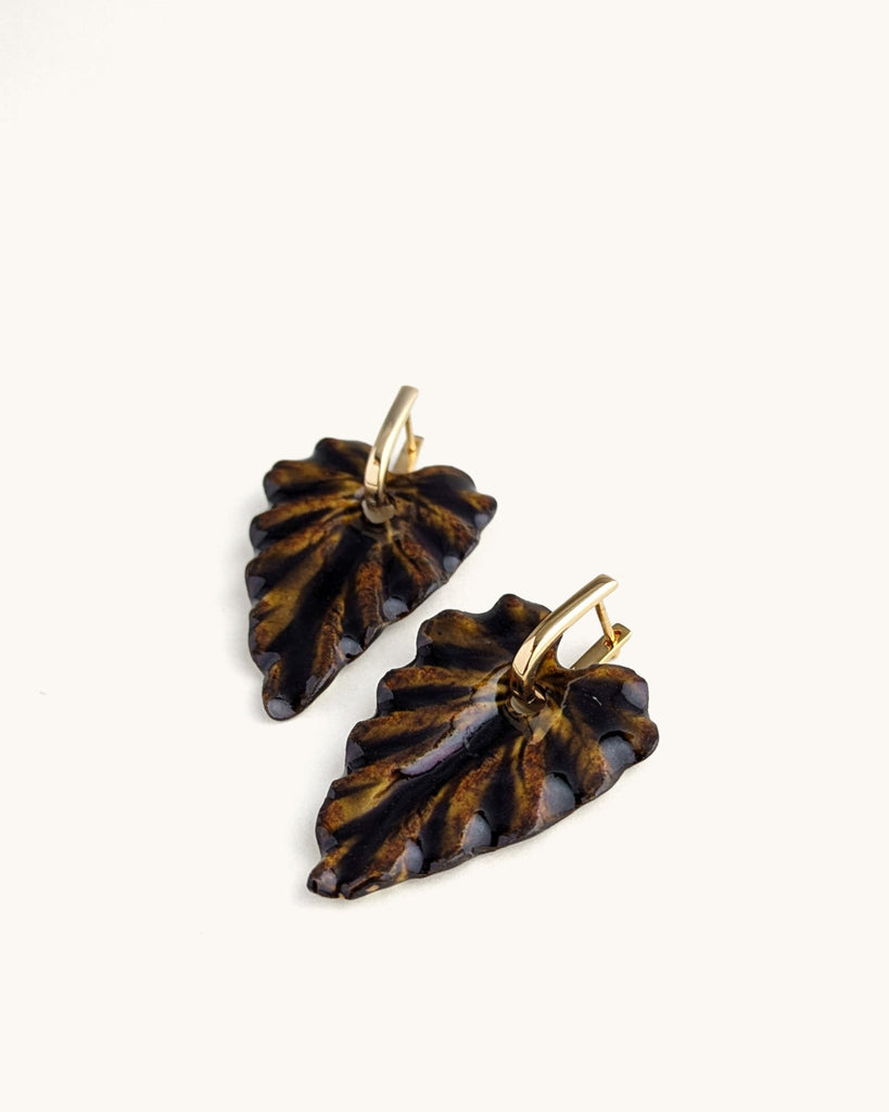 Une feuille sculptée, un brun profond qui évoque la terre, l’écorce, le végétal transformé.
Ces boucles jouent la nature dans ce qu’elle a de plus intense : un volume vivant, texturé, façonné à la main.

Organique, expressive, inattendue — une présence qui réchauffe le visage et affirme le style. Nées de la beauté du végétal, ces boucles explorent les nuances de la botanique et la force silencieuse de ses formes.
Leur relief sculpté, leur lumière changeante et leur étonnante légèreté en font une pièce viva