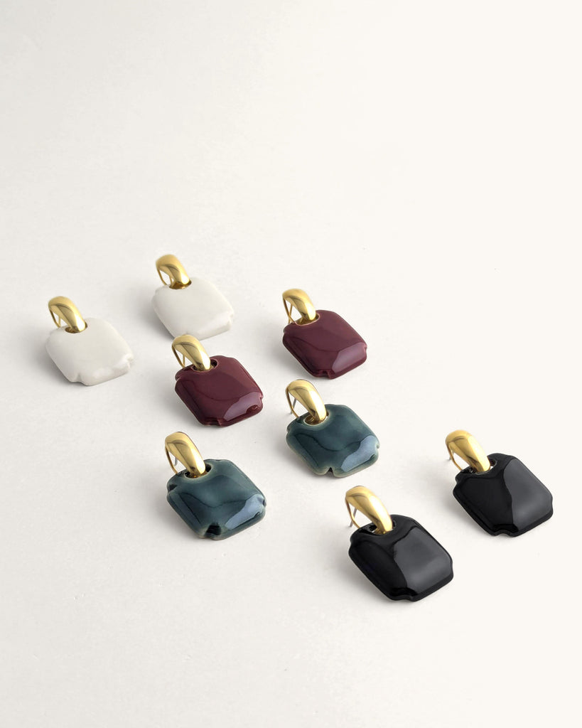 Paire de boucles d’oreilles forme carré arrondi coloris vert céladon, inspiration vintage année 80, au volume géométrique adouci, finition émaillée, montées sur un élément plaqué or.  Bijou contemporain fait main, style minimal et intemporel par Lydie Smith artisan bijoutier et céramiste basée à Paris.