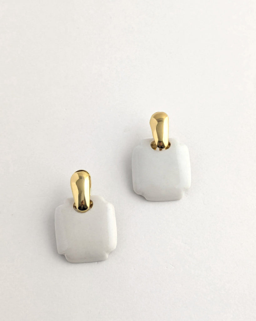 Paire de boucles d’oreilles forme carré arrondi coloris vert céladon, inspiration vintage année 80, au volume géométrique adouci, finition émaillée, montées sur un élément plaqué or.  Bijou contemporain fait main, style minimal et intemporel par Lydie Smith artisan bijoutier et céramiste basée à Paris.