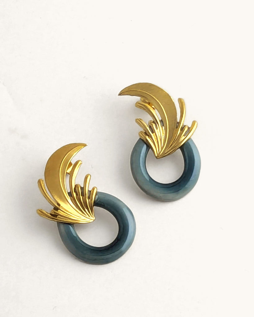 Boucles d’oreilles art déco vert céladon et dorées, ornées d’un motif végétal sculpté rappelant l’élégance des années Gatsby, avec un anneau noir laqué contrastant. Créé par LYDIE SMITH artisan céramiste et bijoutier dans son atelier à Asnières en France