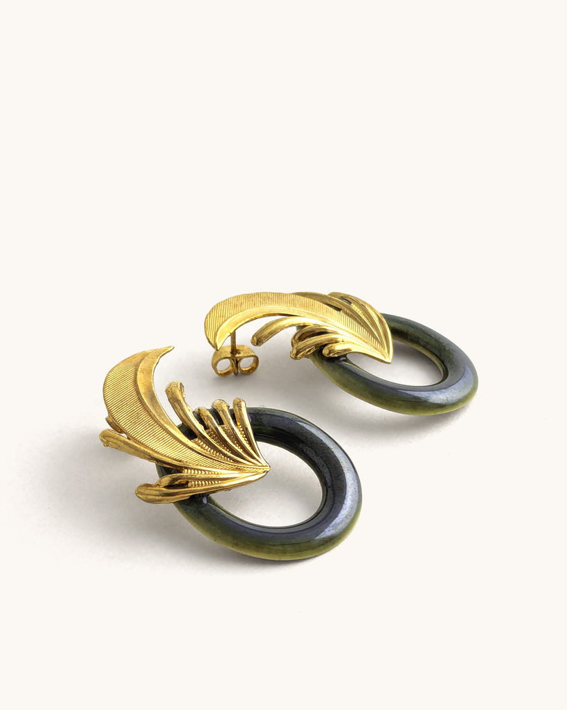 Boucles d’oreilles art déco coloris vert kaki et dorées, ornées d’un motif végétal sculpté rappelant l’élégance des années Gatsby, avec un anneau noir laqué contrastant. Créé par LYDIE SMITH artisan céramiste et bijoutier dans son atelier à Asnières en France