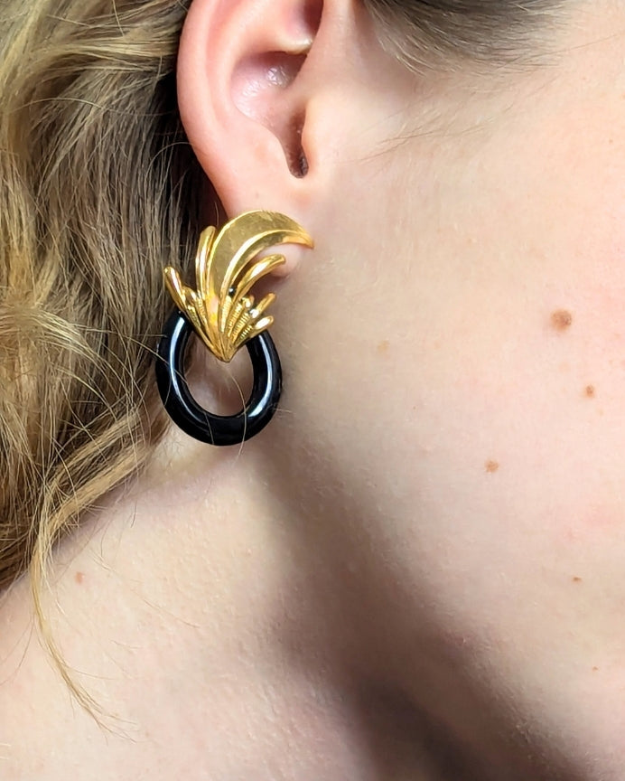 Boucles d’oreilles art déco noires et dorées, portées et ornées d’un motif végétal sculpté rappelant l’élégance des années 30, esprit vintage,  avec un anneau noir émaillé contrastant. Créé par LYDIE SMITH artisan céramiste et bijoutier dans son atelier à Asnières en France